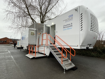 A large white truck with steps leading up to it. The text on the side of the truck reads "Liverpool Heart and Chest Hospital" and "Cheshire and Merseyside Cancer Alliance"